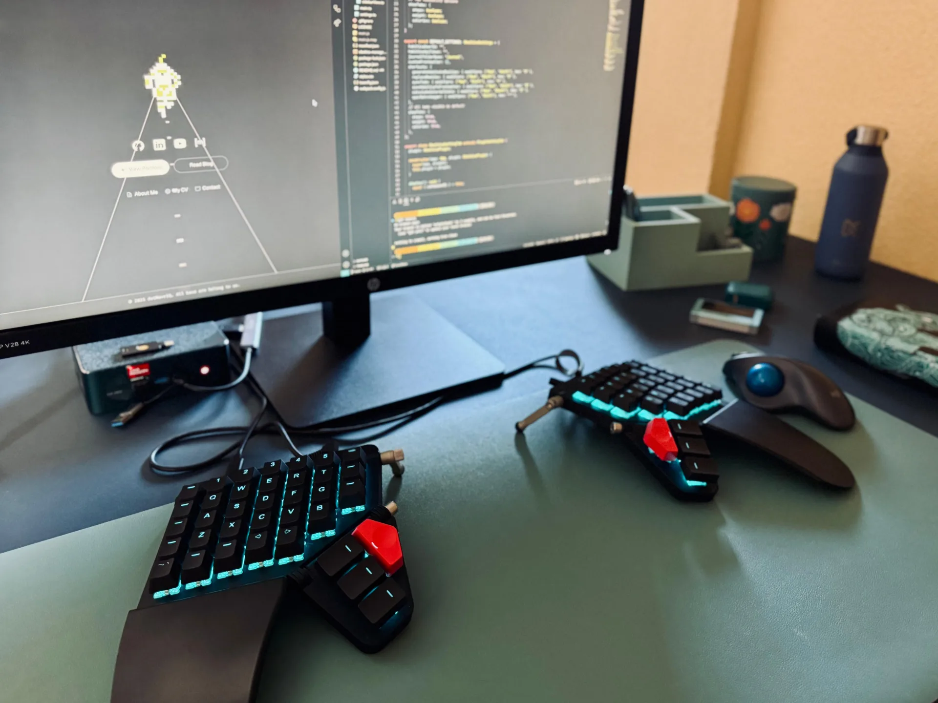 The current setup: Moonlander Mark I split keyboard, Logitech M575S trackball, and HP V28 4K monitor on the IKEA Bekant.